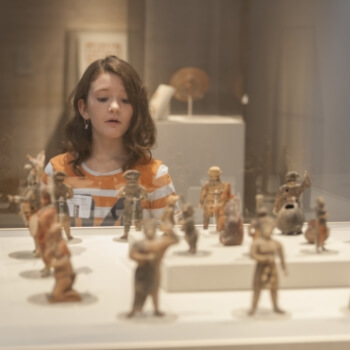 a girl admiring small figures in the Fiery Pool: The Maya and the Mythic Sea exhibition
